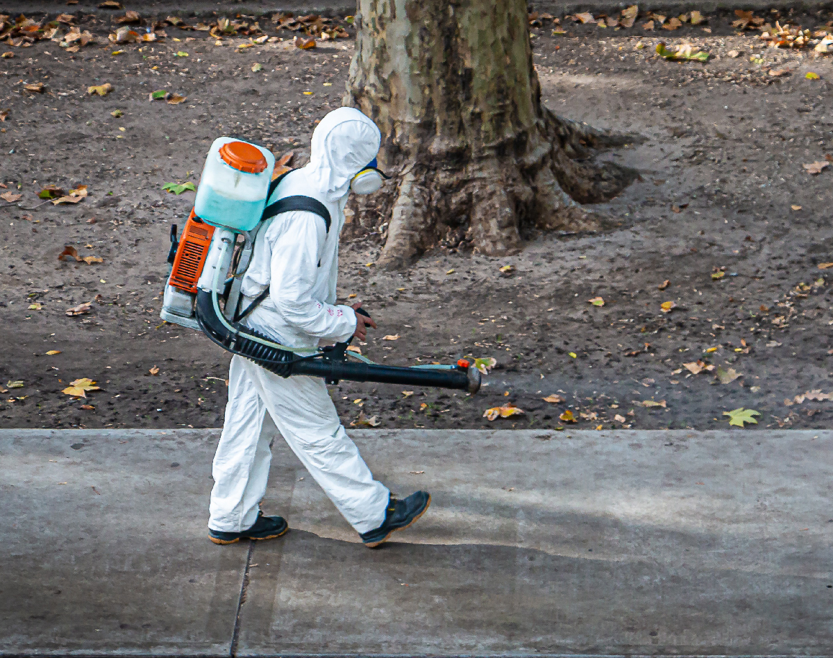 Person in hazmat suit sanitizing street