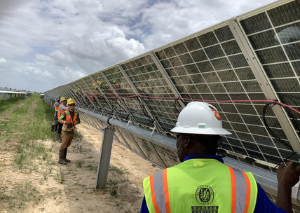 Men standing infront of solar panel