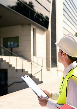 Person holding clipboard and wearing PPE looking at front door of building