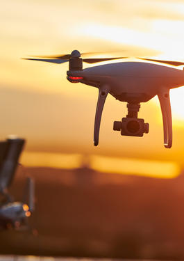 Small Drone flying at eye level with the operator standing in the background