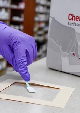 Someone using the ChemoAlert to sample their workspace