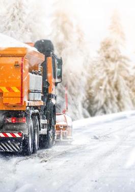 Salt truck driving on a road while it is snowing