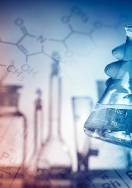Hand holding beaker with images of compound structures and the periodic table in the background