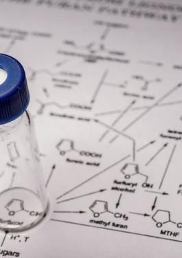 Composition of a compound written down a paper with a sample jar sitting at the bottom