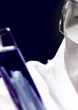 Close up of woman in goggles looking at liquid in a purple test tube