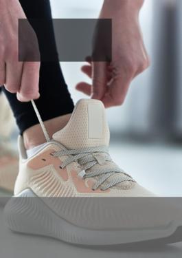 close up of person tying a pair of cream sneakers