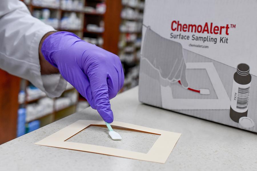 Someone using the ChemoAlert to sample their workspace