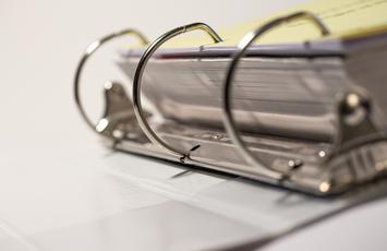 Zoomed in photo of a binder with a large ream of documents inside.