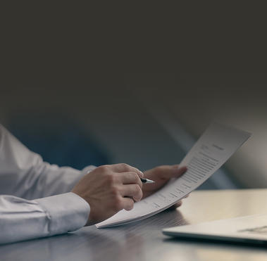 Male arms with pen in hand reviewing documents