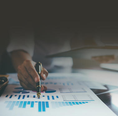 Charts laid out on a table with someone holding a pen marking them